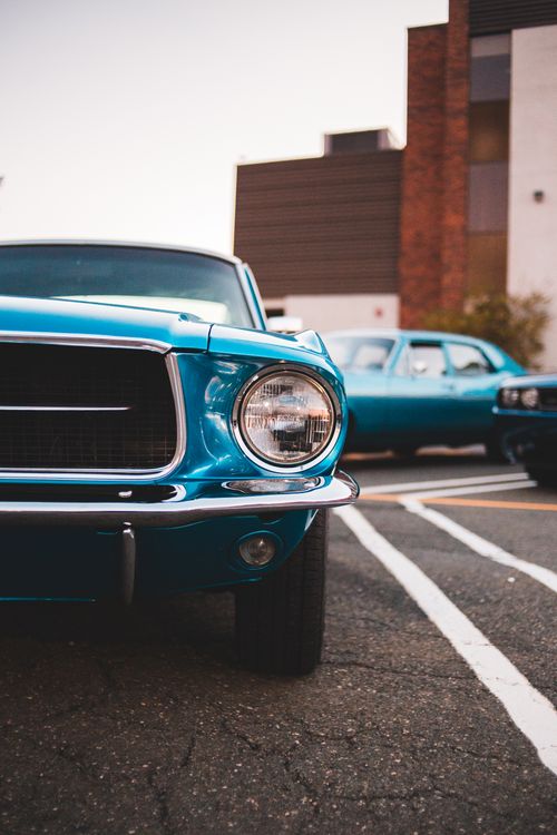 Free Front view of a classic blue car, shining under the daylight in an urban setting. Stock Photo