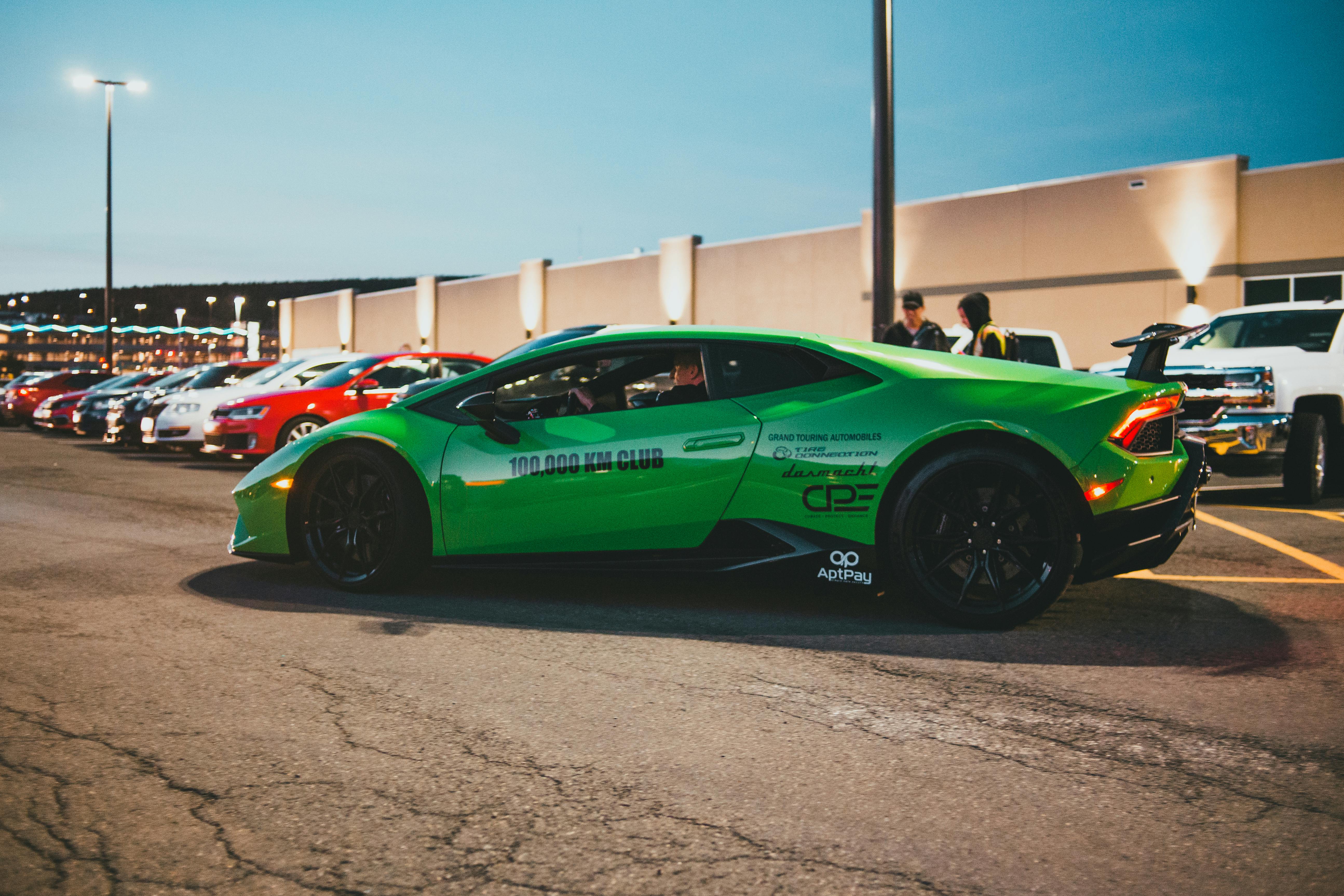 Free Side view of a green Lamborghini parked outdoors with other vehicles. Stock Photo