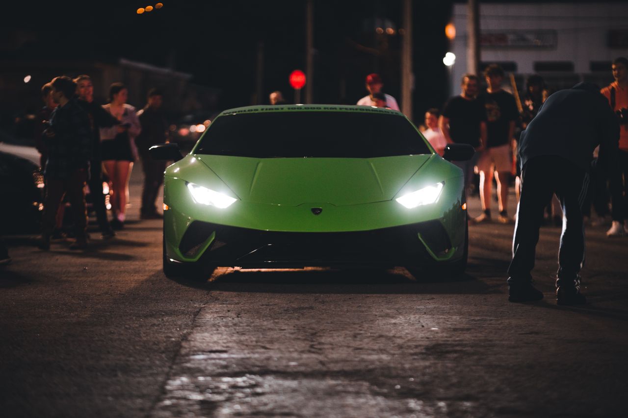 a vibrant green lamborghini huracan showcased among a crowd during a n