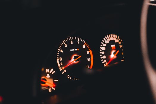 Detailed view of illuminated Nismo car gauges displaying the speedometer and tachometer.