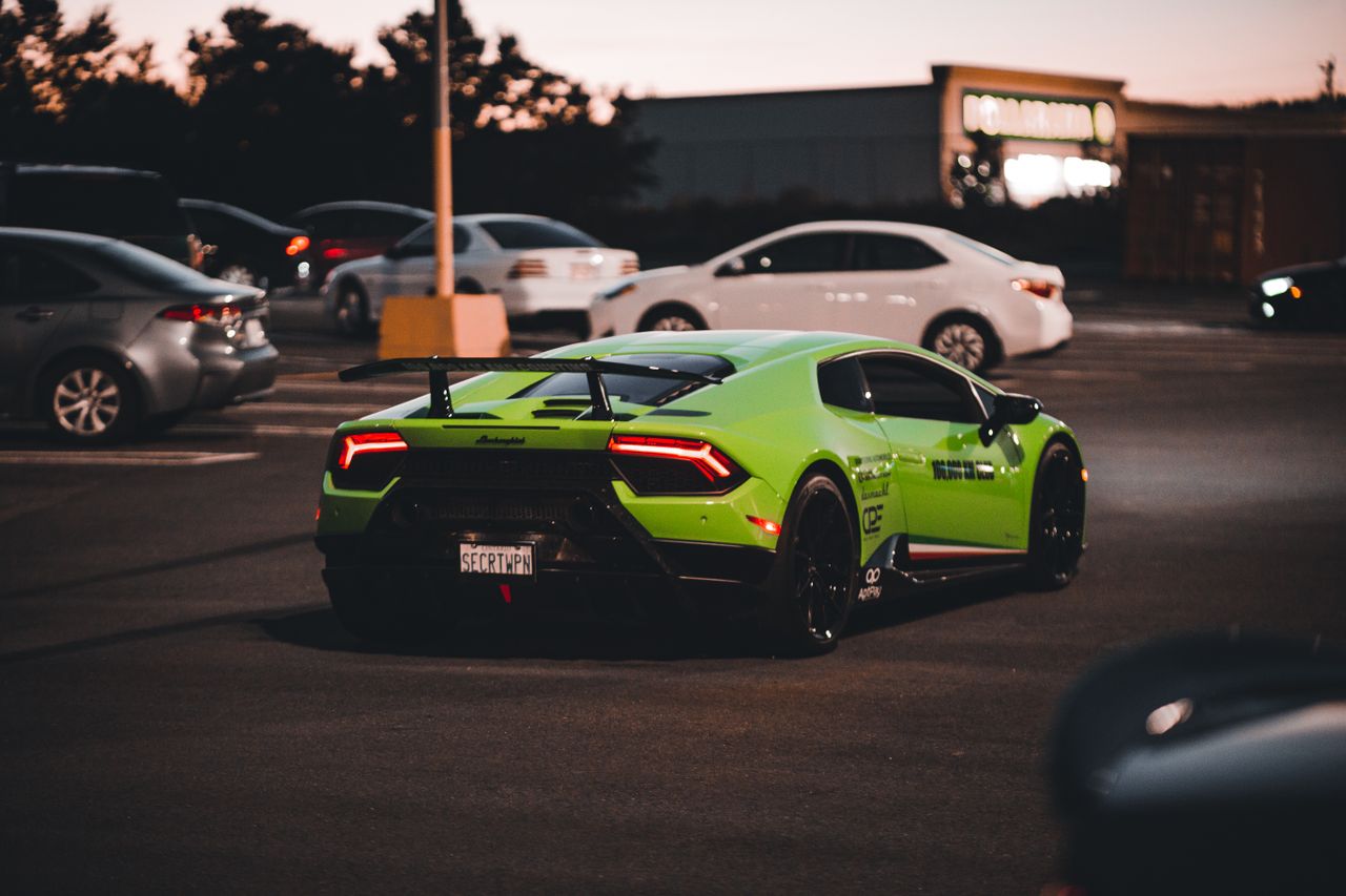 a vibrant green sports car parked with other vehicles at dusk dynamic