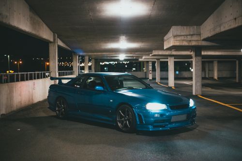 Free Blue sports car with headlights on in a dimly lit underground parking garage. Stock Photo