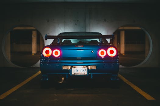 Blue sports car with illuminated tail lights parked in a dimly lit garage.