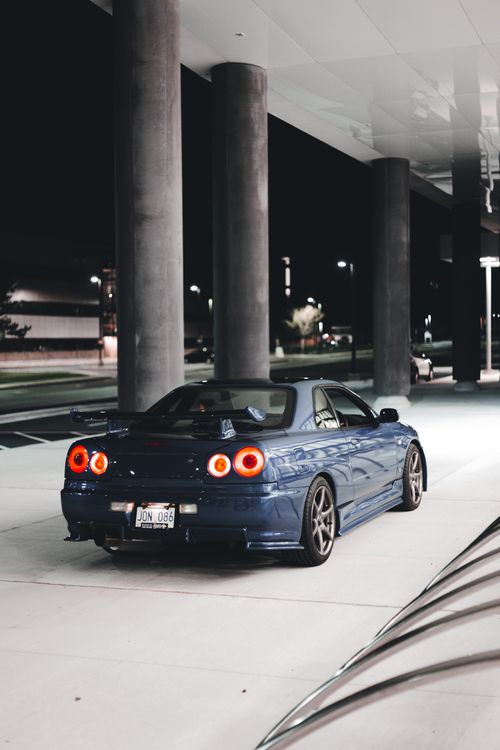 Free Elegant blue sports car parked under urban streetlights, highlighting modern design elements. Stock Photo