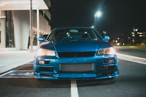Free Front view of a blue sports car parked at night under streetlights. Stock Photo