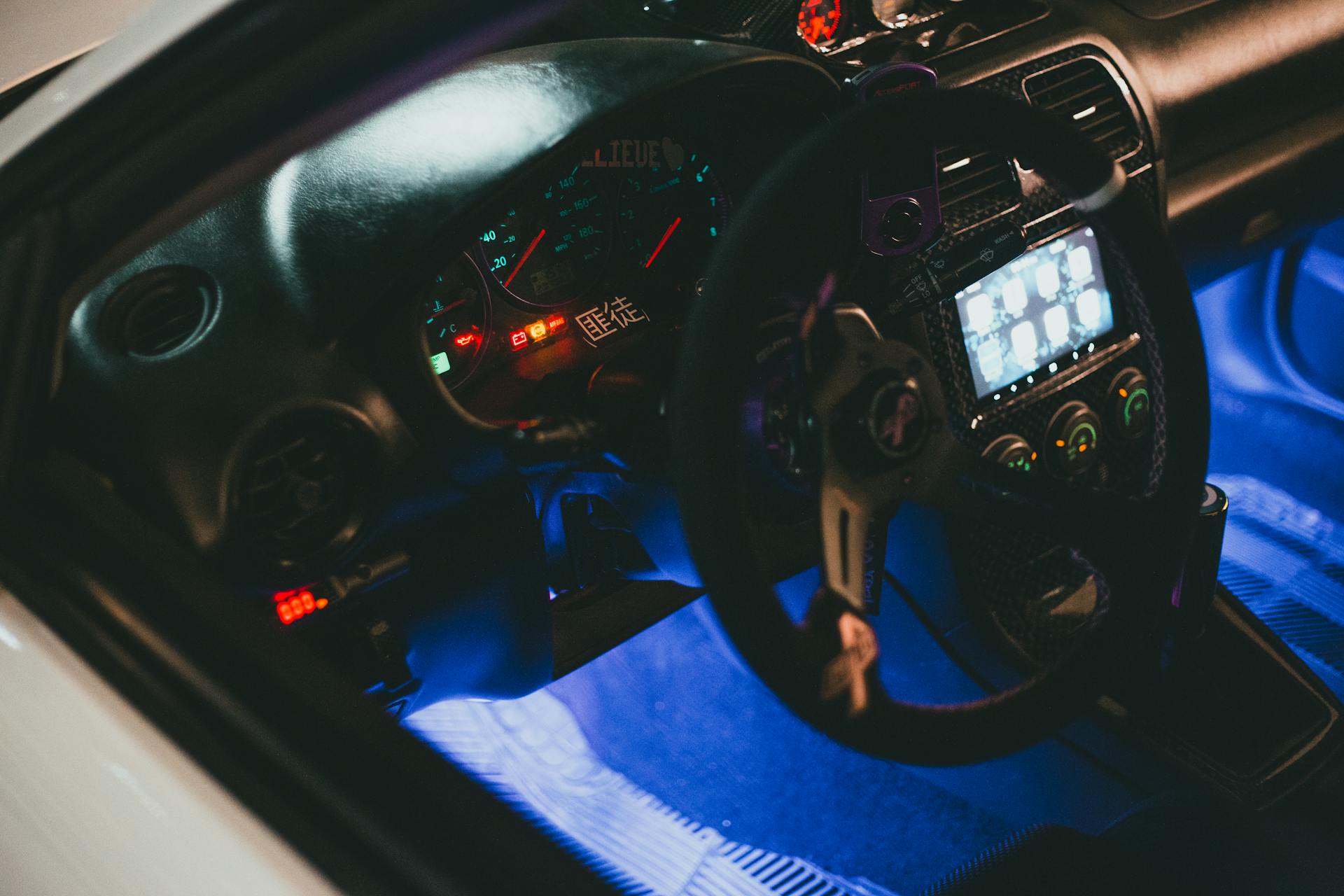 Close-up of an illuminated car interior featuring dashboard gauges and steering wheel.