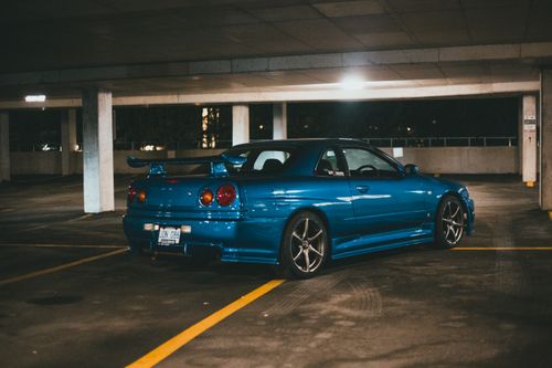 Free A sleek blue Nissan Skyline sports car parked in an underground garage at night. Stock Photo