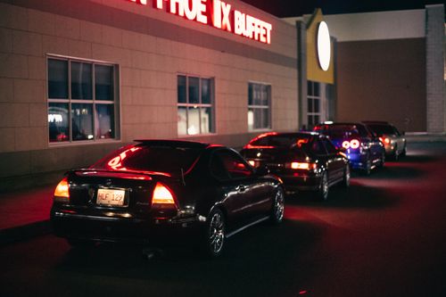 Free Cars lined up in a parking lot at night outside a buffet restaurant, illuminated by tail lights. Stock Photo