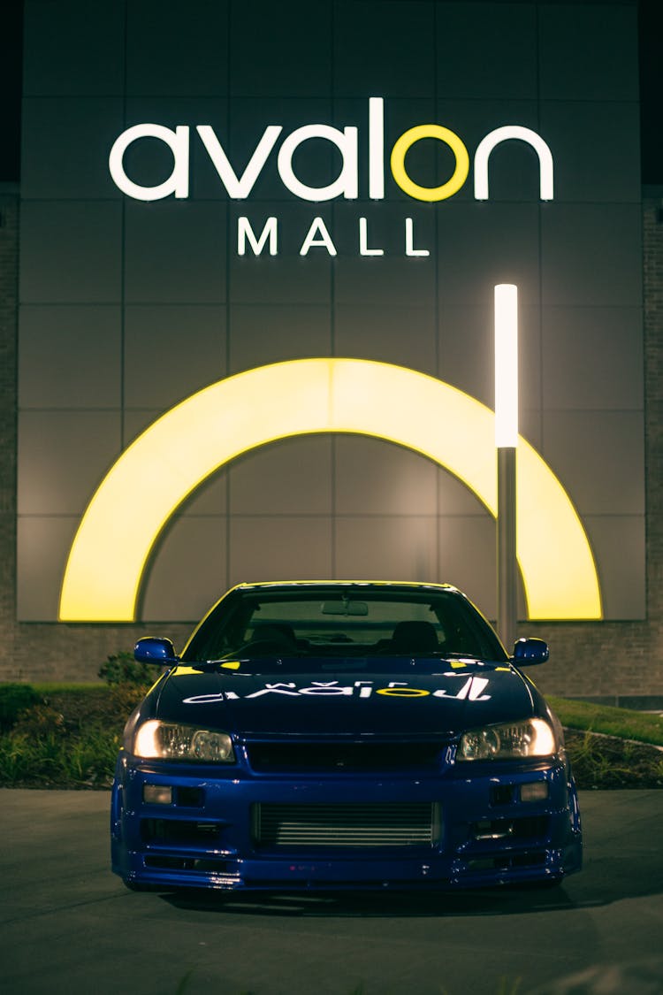 A Blue Shiny Car Parked Outside A Mall