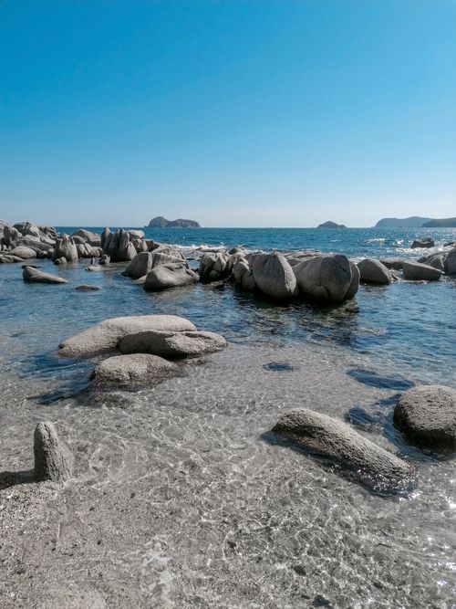 Free Stunning view of rocky coastline with clear blue sky and crystal-clear water. Stock Photo