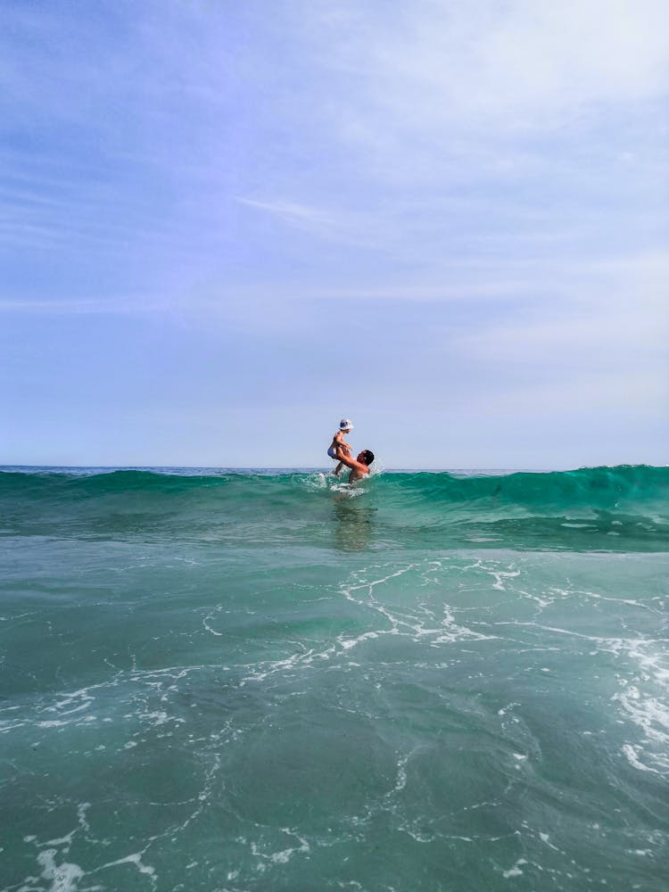 Man Standing At The Ocean Raising His Baby