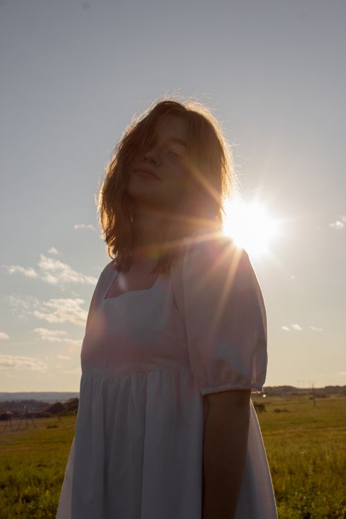 Free A woman stands in a sunlit field, creating a serene outdoor atmosphere. Stock Photo