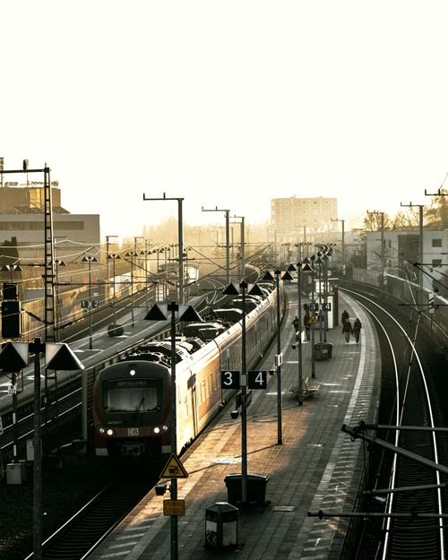 Free A train departs from a sunlit station platform at dusk, capturing urban transportation. Stock Photo
