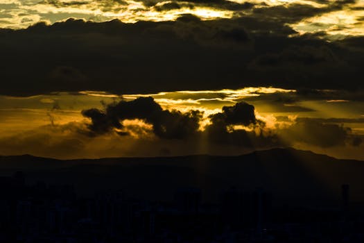 A stunning city silhouette with dramatic clouds and golden sunset rays.