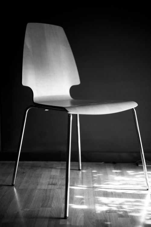 Free Artistic black and white photo of a modern metal chair on wooden floor. Stock Photo