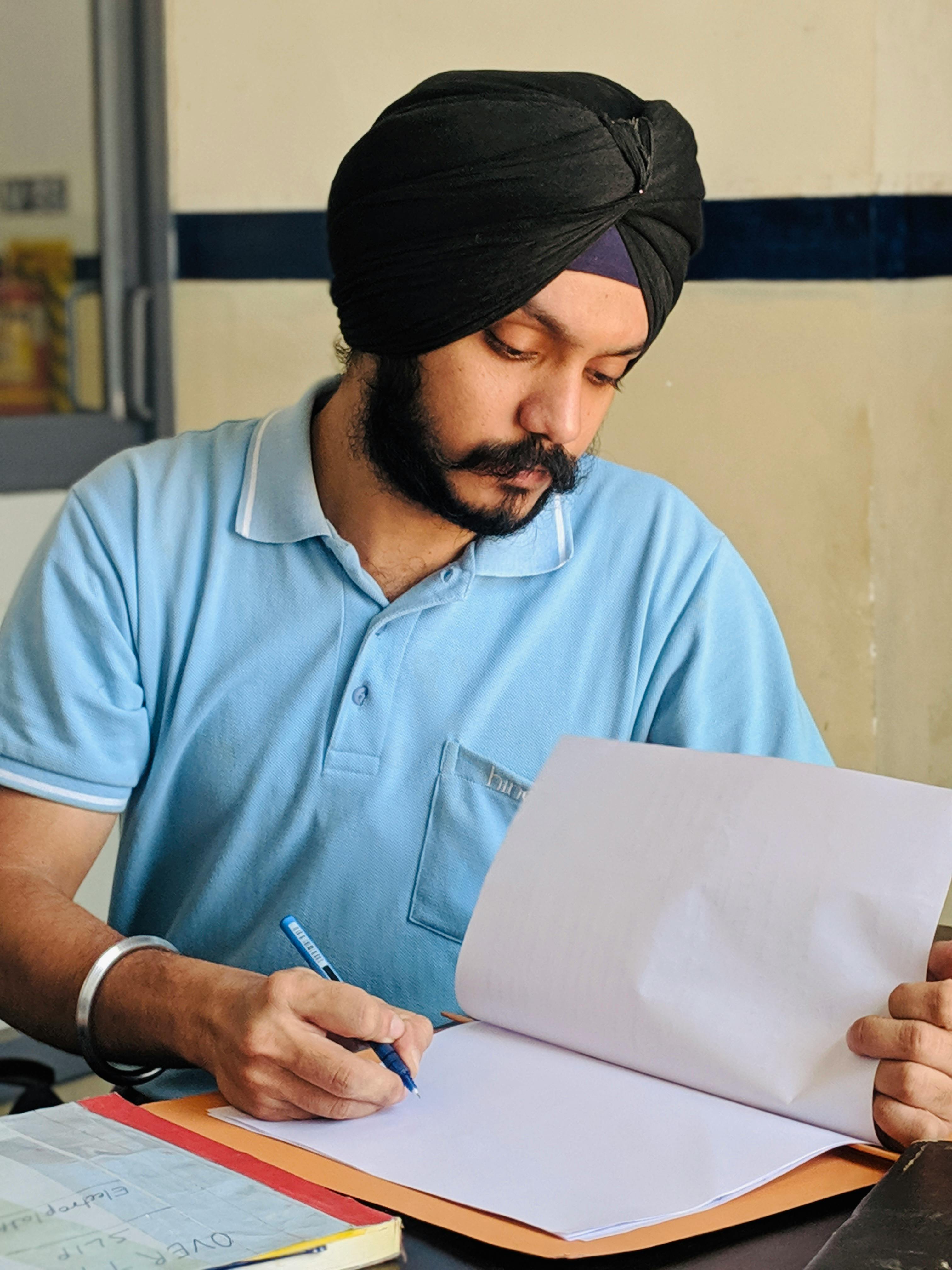 an indian man wearing a turban is reading a book