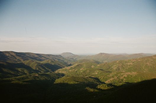A picturesque mountain valley view with lush greenery under a clear sky, captured at dawn.