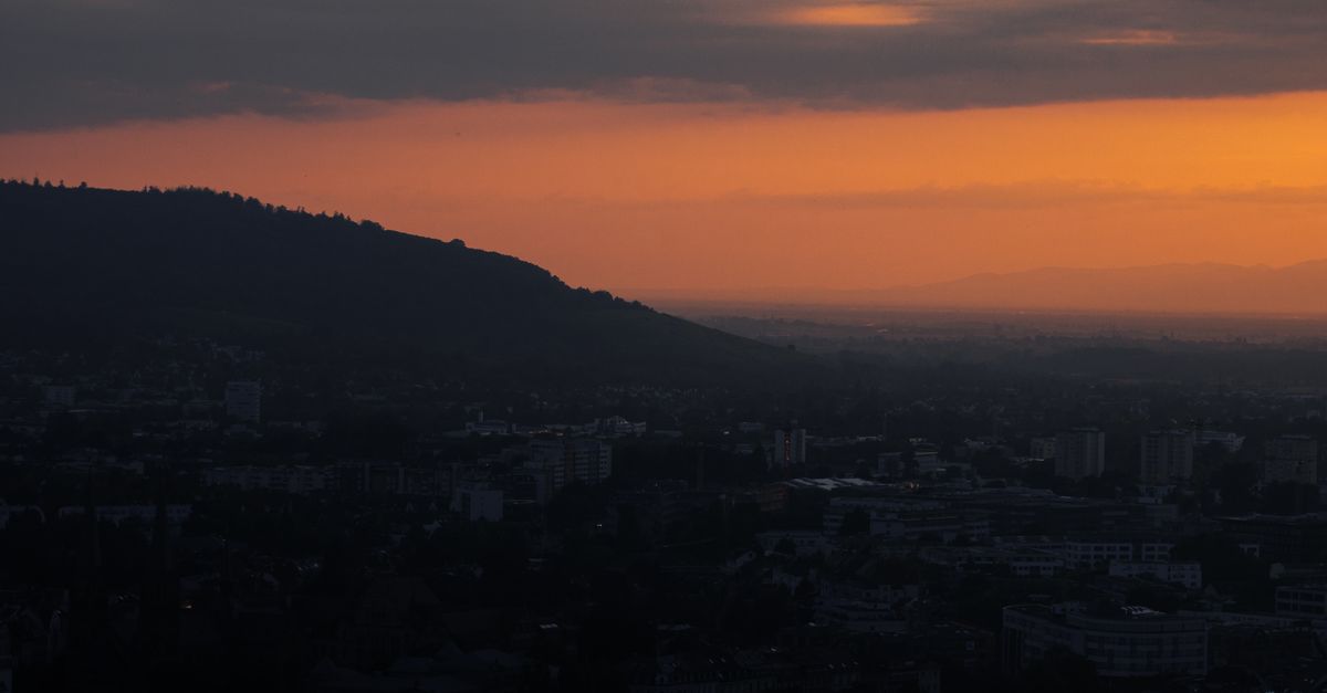 Beautiful aerial sunset view over Freiburg cityscape with silhouetted hills.