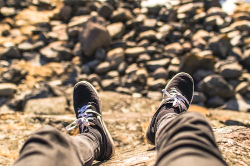 Free Shallow Focus Photography of Person Wearing Gray Jeans Sitting in Front Rocks Stock Photo