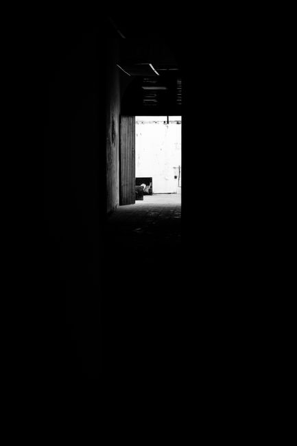 A dark hallway leading to a bright, open space creates a striking contrast.