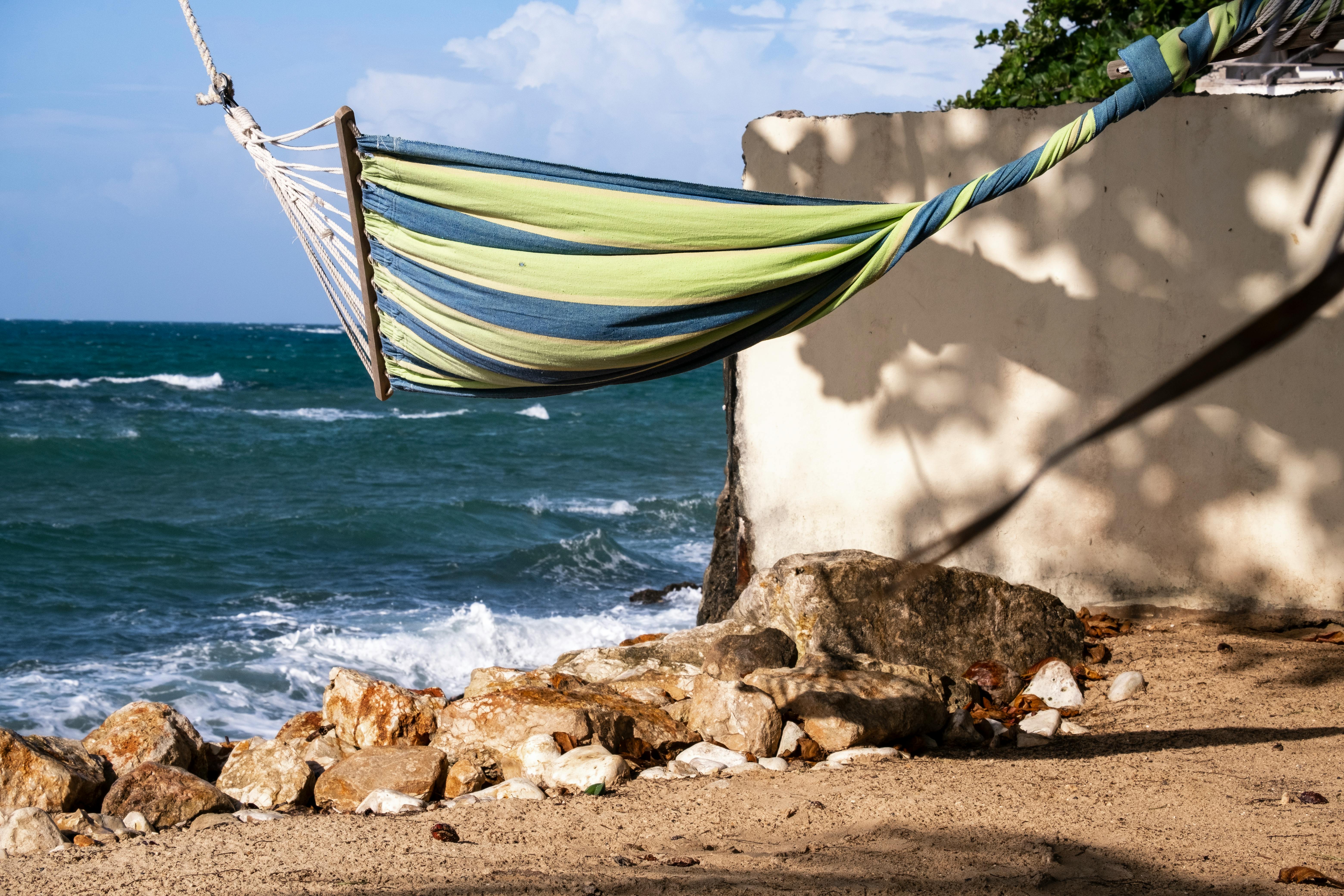 A serene beach scene with a colorful hammock overlooking the ocean, surrounded by rocks and sand. - Montego Bay
