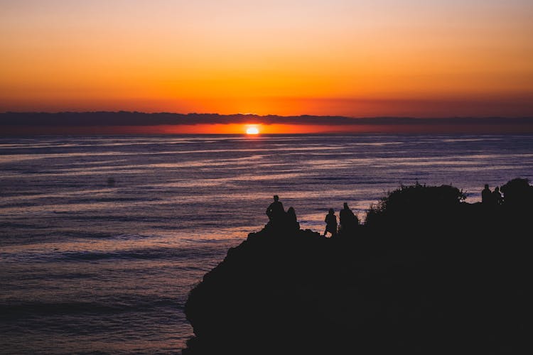 Silhouette Of People On Mountain Looking At Sunset View