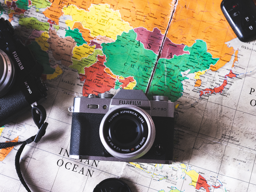 Flat lay image featuring vintage cameras placed on a colorful world map, ideal for travel themes.