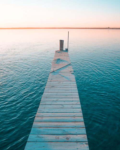 Free Tranquil view of a wooden pier extending into a calm lake at sunset in Traverse City, Michigan. Stock Photo