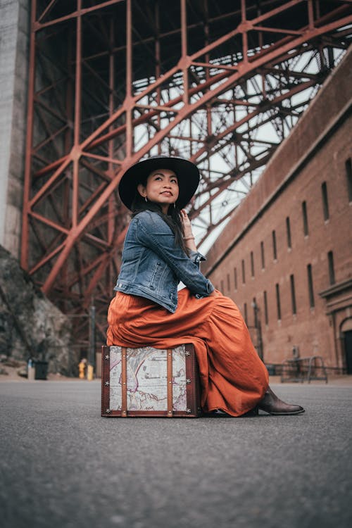 Woman in Denim Jacket Sitting on a Luggage