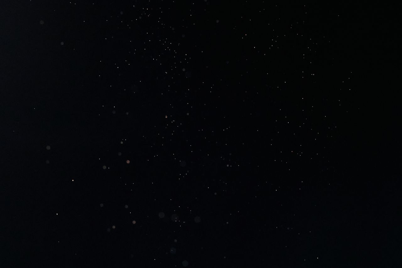 dark black background featuring scattered tiny particles ideal for tex