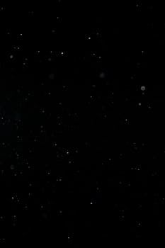 Abstract black background showcasing tiny dust particles in motion.