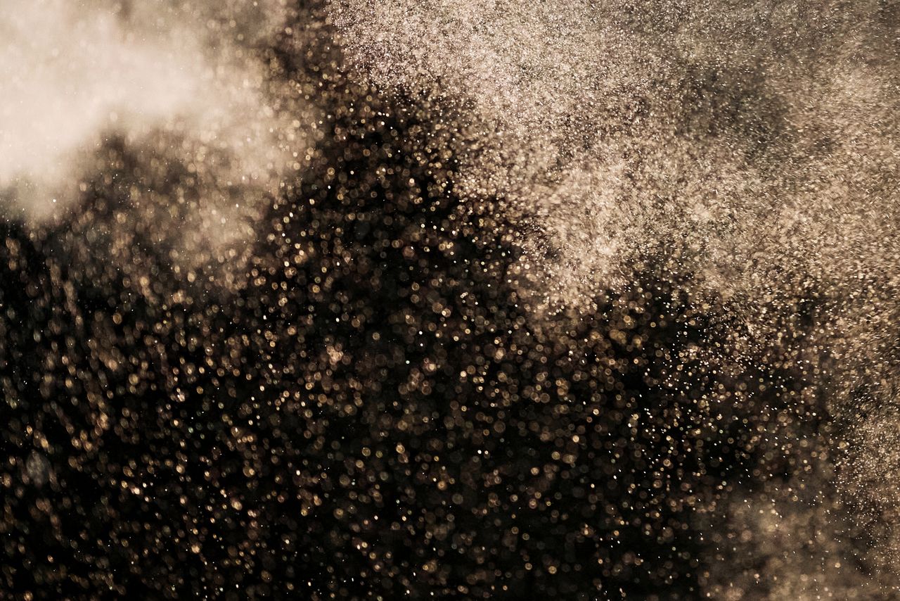 Gold particles floating against a dark background creating a magical atmosphere