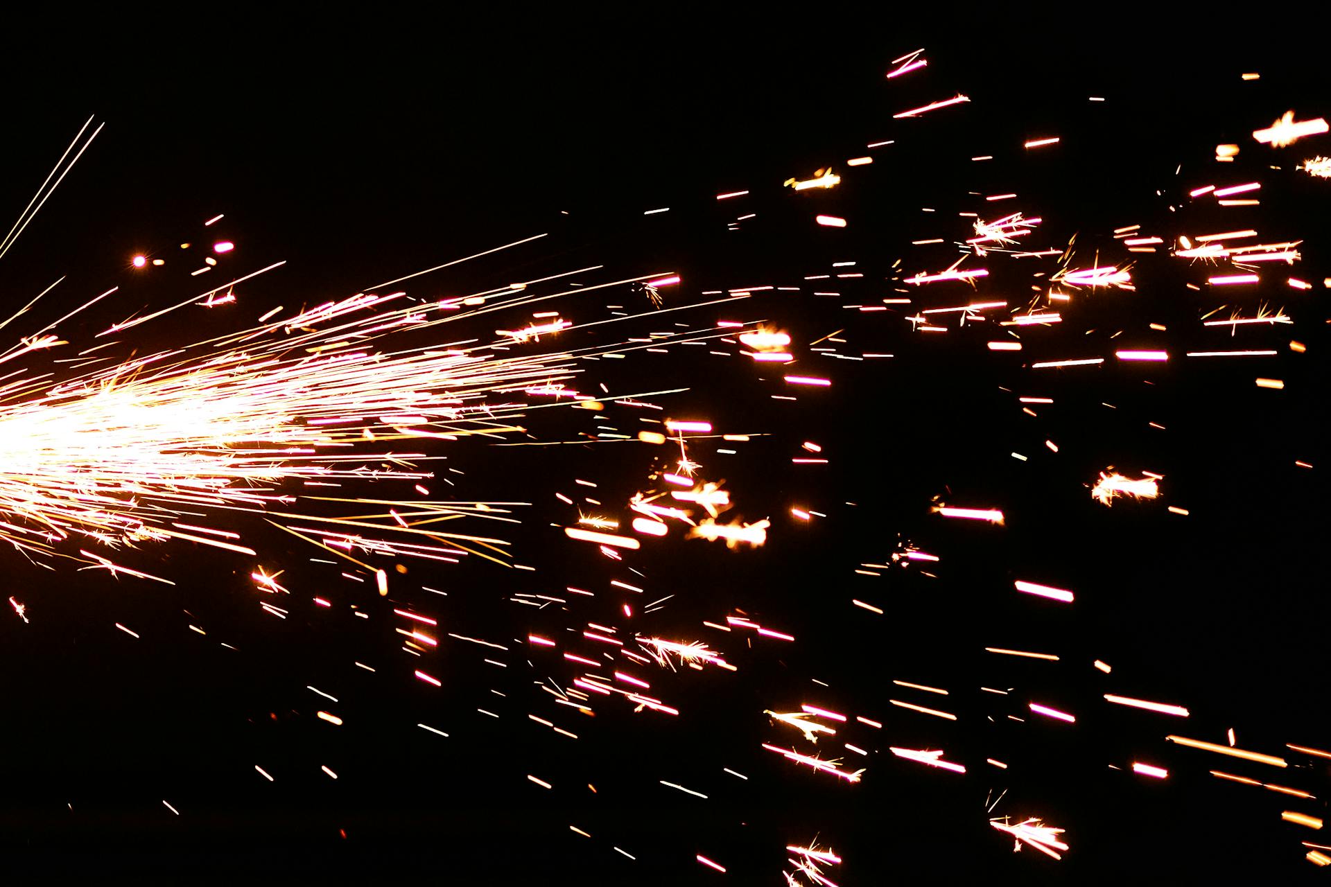 Close-up of bright sparks igniting and streaking across a black background.