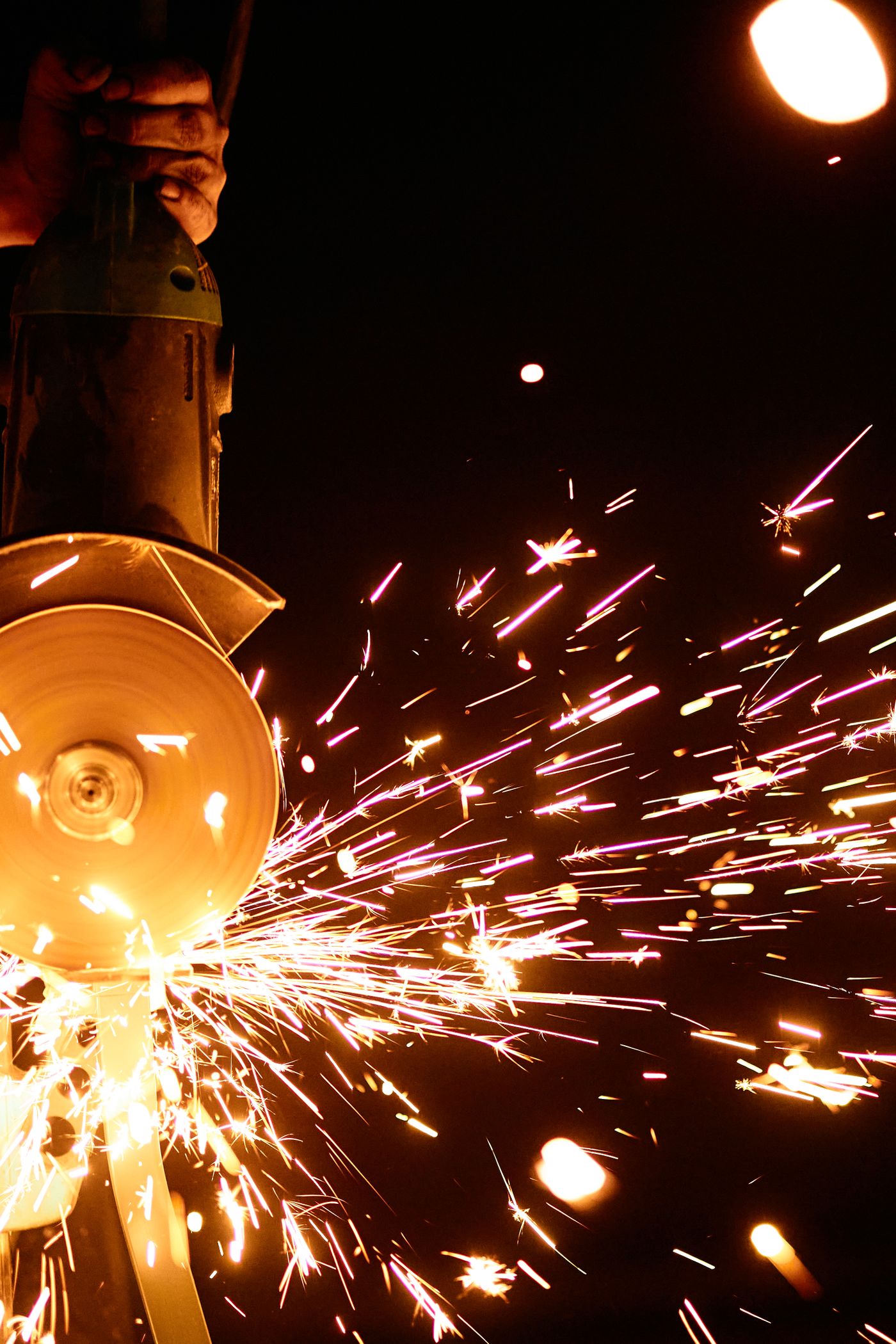 Sparks streaming from a grinding wheel in a dark workshop.