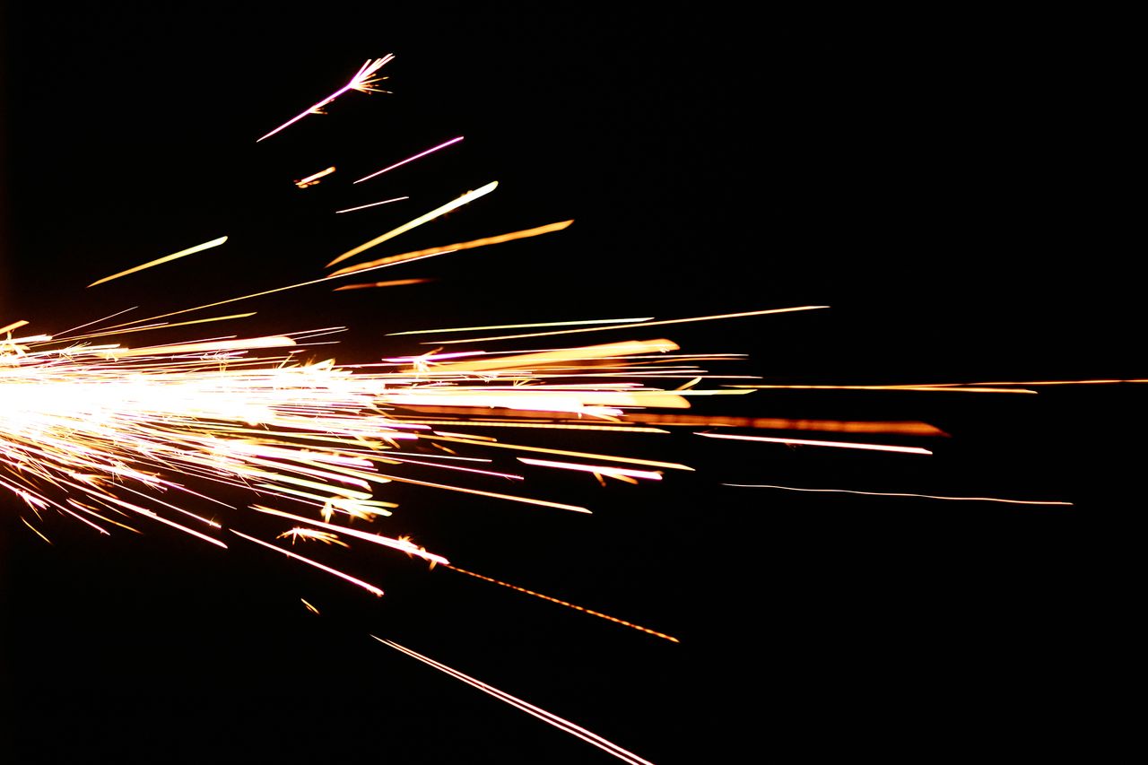 close up of bright sparks flying against a dark background creating a