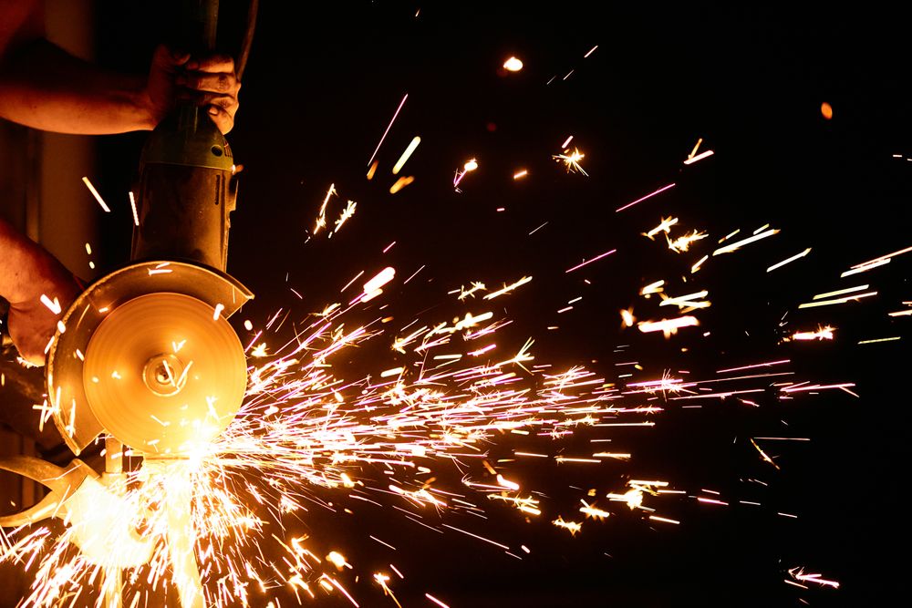 Angle grinder dressing a weld, a dense shower of sparks in a dark shop.
