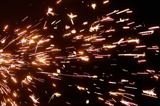 Close-up view of vibrant sparkler sparks illuminating a dark background.