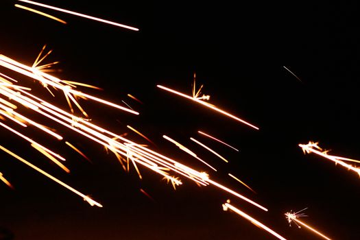 Captivating shot of bright orange sparks against a black backdrop, creating a dynamic effect.