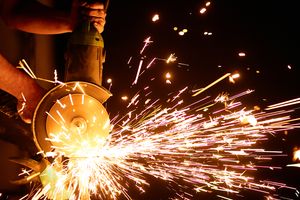 Metalworker grinding steel with bright sparks