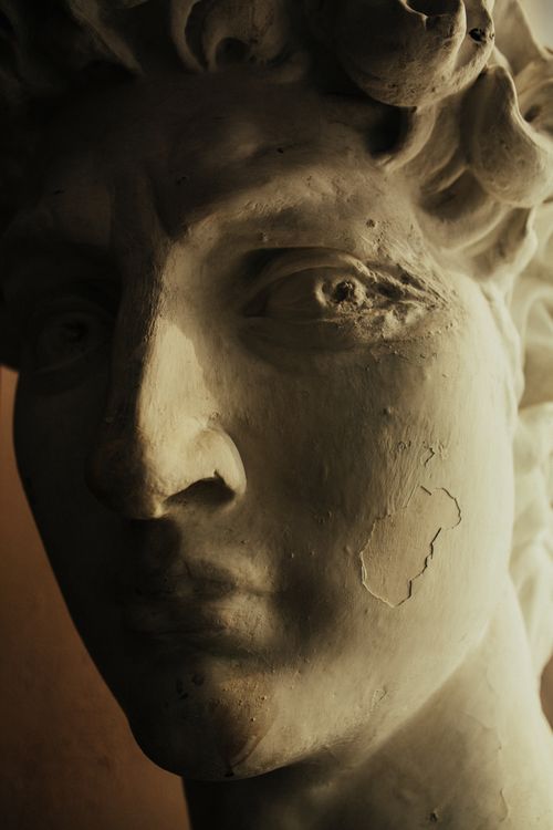 Free Detailed close-up of a weathered classical marble sculpture showcasing shadows and sunlight effects. Stock Photo