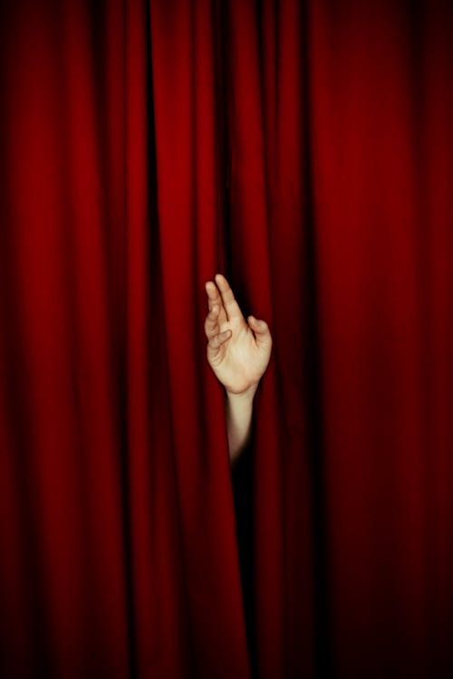 Human hand from behind curtain in theatre 