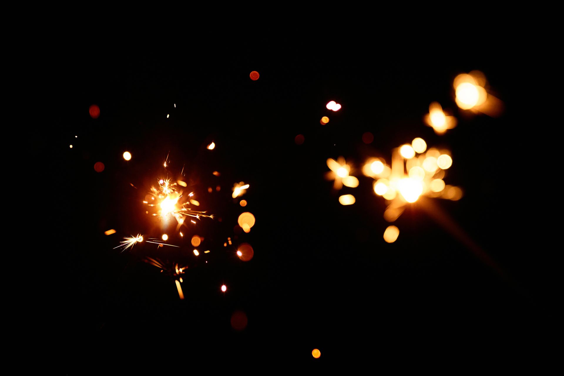 Bright and dazzling sparks creating a warm bokeh effect against a black background.
