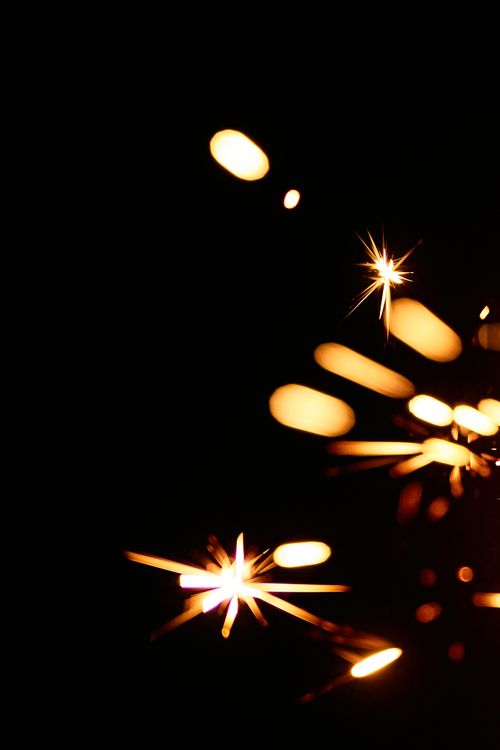 Free Vivid close-up of a burning sparkler against a dark background, showcasing shimmering and vibrant sparks. Stock Photo