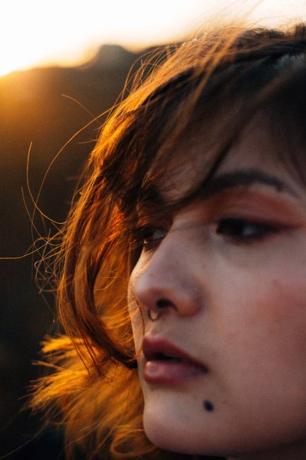 Close-up of a woman with long hair looking away in sunlight.