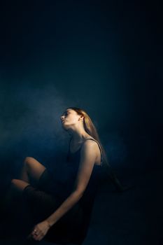 Artistic portrait of a woman in low light with dramatic smoke effects.