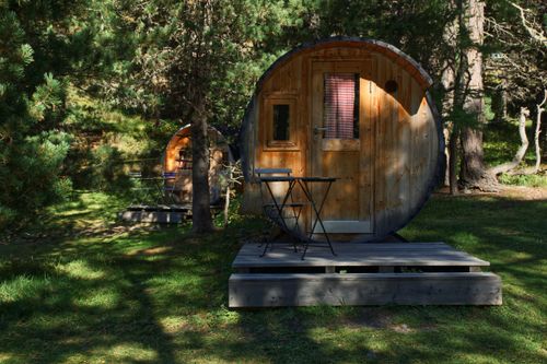 Free Cozy round wooden cabins in a serene forest with rustic outdoor seating, perfect for nature retreats. Stock Photo