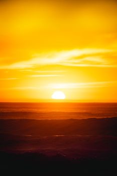 Golden sunset casting vibrant hues over the ocean waves in California, creating a picturesque seascape at dusk.