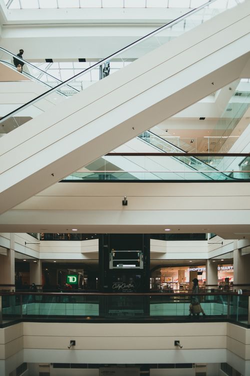 Free Interior view of a modern shopping mall with multiple escalators and retail stores, showcasing architectural design. Stock Photo