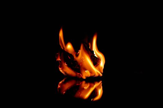 A mesmerizing flame creating dramatic reflections on a black surface.