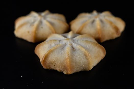 Three homemade shortbread cookies beautifully arranged on a black surface.